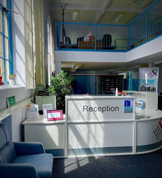 Recepción del centro con mostrador blanco, zona de espera y balcón superior