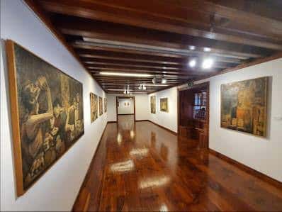 Interior de la galería de arte con obras expuestas y suelo de madera pulida