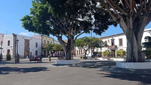 Vista panorámica de la plaza con grandes árboles y bancos para visitantes