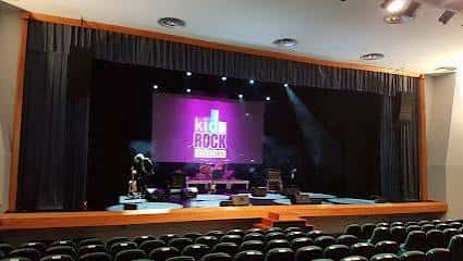 Interior del auditorio con escenario iluminado y butacas durante un evento