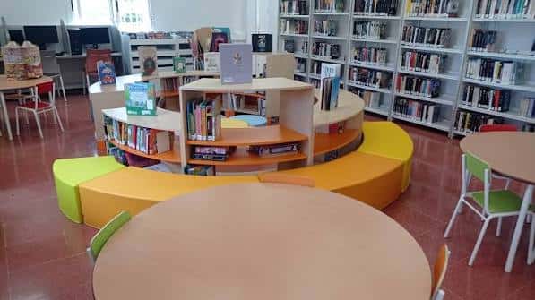 Interior de la biblioteca con estanterías curvas, zonas de lectura y mobiliario colorido para niños