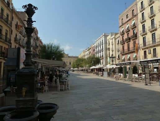 Vista panorámica de la Plaça de la Font con la fuente ornamental en primer plano y edificios históricos al fondo