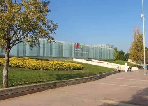 Vista panorámica de la biblioteca desde el parque con césped y árboles