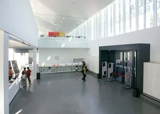 Interior del hall de la biblioteca con zona de lectura y escaleras