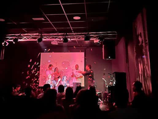 Evento con público y confeti en el interior del Café Teatro Rayuela bajo luces rojas