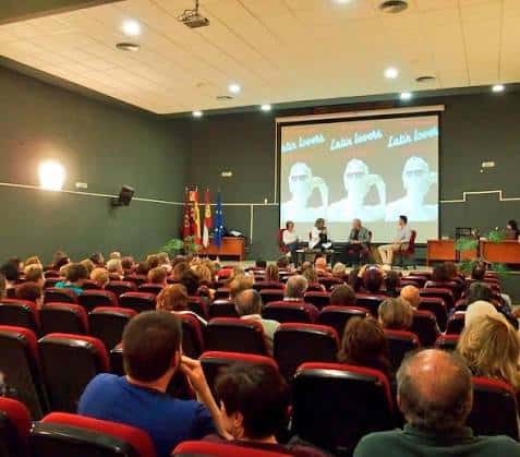 Interior del auditorio durante un evento con público y panel de ponentes