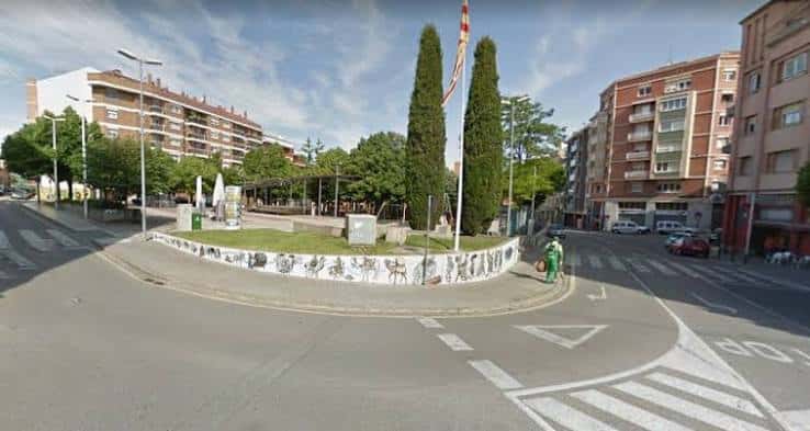 Plaza circular con banderas catalanas y murales decorativos en el borde