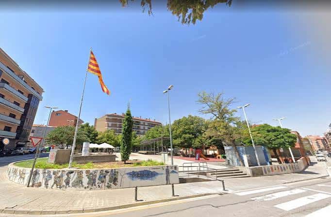 Plaza con bandera de Cataluña ondeando y zona de juegos infantiles