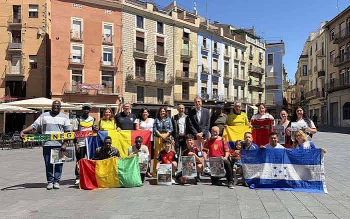 Grupo de personas con banderas internacionales en la plaza, mostrando diversidad cultural