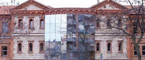 Vista frontal del edificio con fachada de ladrillo y piedra y sección de cristal moderno en el centro