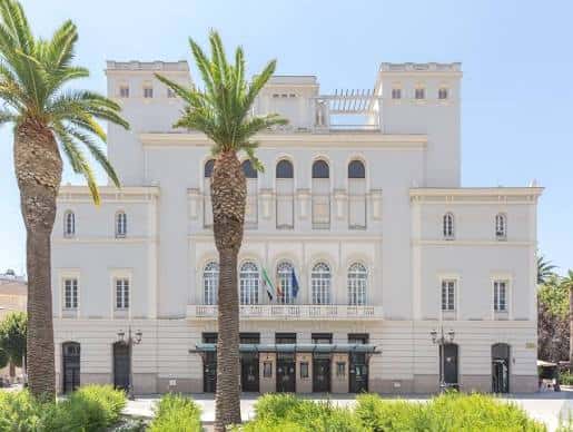 Vista exterior del Teatro López de Ayala con fachada neoclásica y palmeras