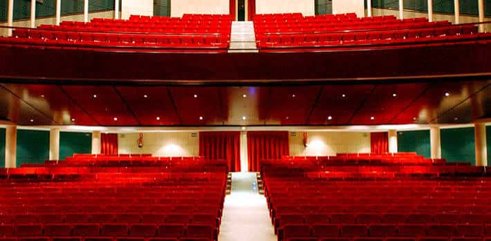 Interior del teatro con butacas rojas y cortinas de escenario