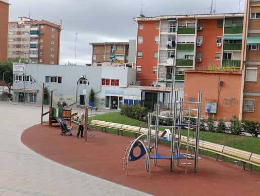 Área de juegos infantiles en la plaza con zonas verdes y bancos