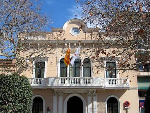 Vista frontal del antiguo edificio del Ayuntamiento de Sant Cugat con fachada clásica y banderas
