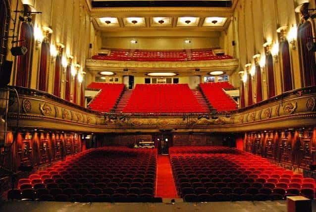 Interior del teatro con iluminación cálida y decoración clásica en los balcones