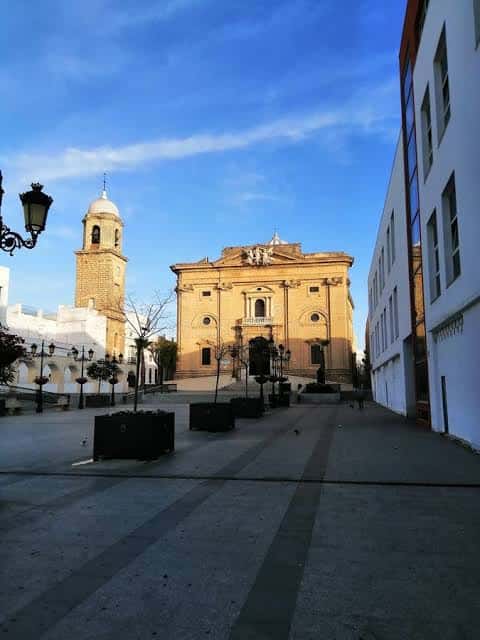 Plaza Mayor al atardecer, mostrando la fachada de la iglesia y la torre iluminadas por la luz dorada del sol