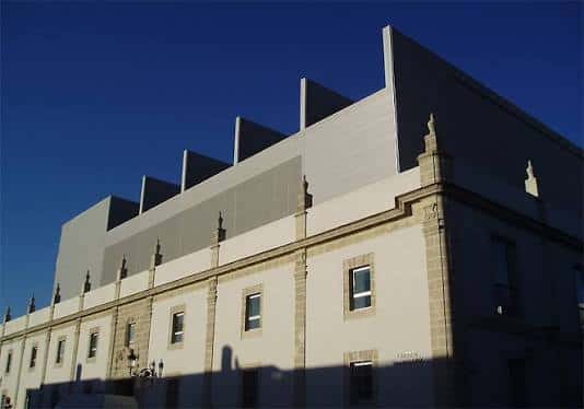 Fachada del teatro con cielo azul despejado, destacando la arquitectura clásica y la estructura contemporánea