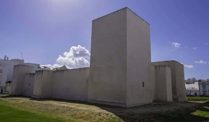 Ángulo lateral del castillo mostrando sus torres y muros bajo el sol
