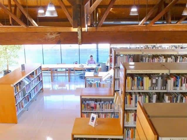 Interior moderno de la biblioteca con estanterías de madera y grandes ventanales