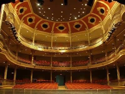 Interior del teatro con balcones ornamentados y butacas rojas