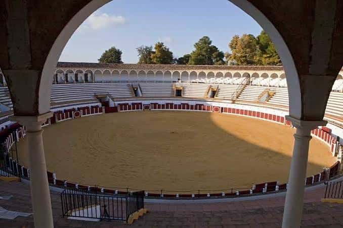 Vista del interior de la plaza de toros desde un arco, mostrando la arena y las gradas vacías