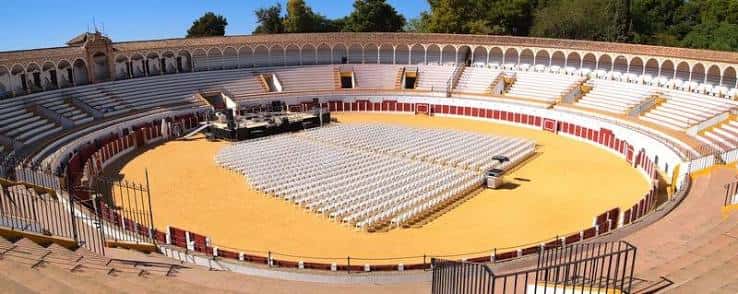 Plaza de toros preparada para un evento con sillas blancas dispuestas en el ruedo
