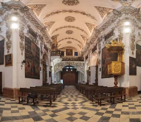 Nave principal de la iglesia con suelo de baldosas y retablo dorado al fondo