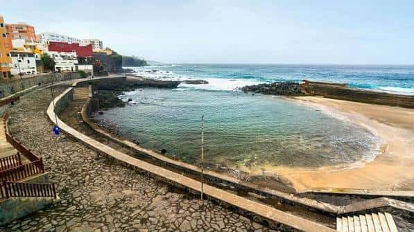 Piscina natural de Bajamar con arena y olas del mar en primer plano
