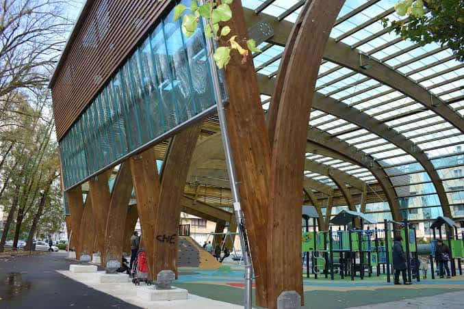 Detalle de la estructura arquitectónica con vigas de madera y el área de juegos al fondo