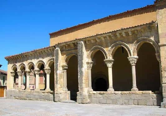 Vista panorámica del atrio de la iglesia de San Lorenzo con sus arcos y columnas románicos bajo un cielo azul