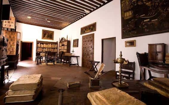 Sala de lectura histórica con estanterías de madera y mobiliario antiguo
