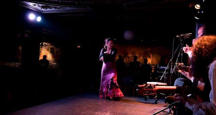 Escenario con bailaora de flamenco en plena actuación bajo iluminación dramática