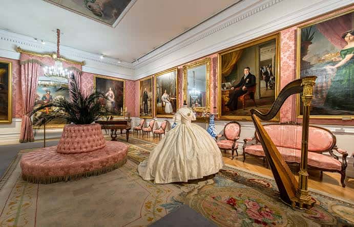 Salón de recepciones con mobiliario romántico y retratos enmarcados