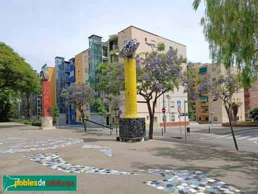Plaza del monumento con detalles de los elementos escultóricos y árboles en flor