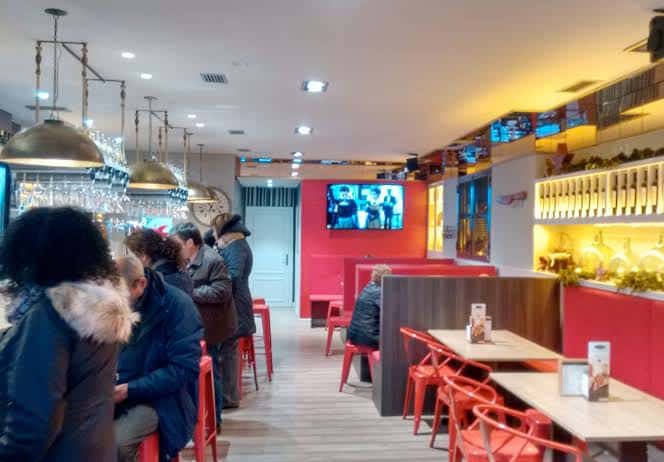 Interior de Cafetería El Valle con clientes, barra y decoración moderna en tonos rojos