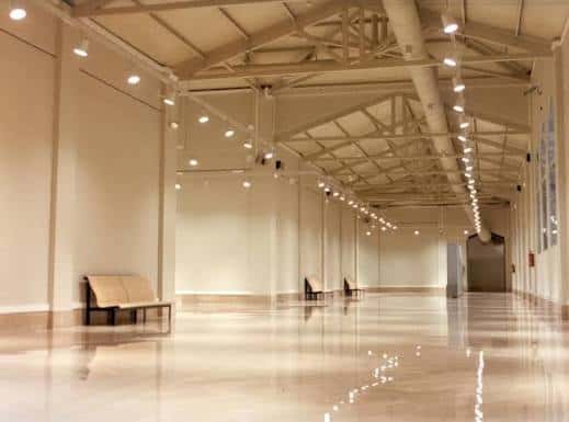 Vista del espacio expositivo vacío, ideal para eventos, con iluminación cenital y estructura metálica visible