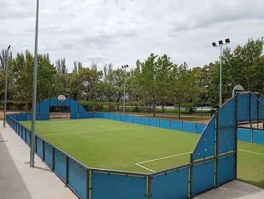 Campo de fútbol con césped artificial y vallas azules en la Ciudad Deportiva