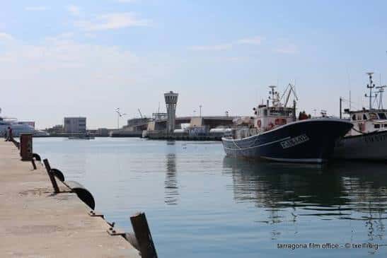 Embarcaciones pesqueras amarradas en el muelle con la torre de control al fondo