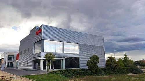 Edificio moderno con fachada metálica y logotipo rojo de 'Tecnalia' bajo cielo nublado