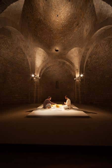 Interior del Bòlit Sant Nicolau con bóvedas de piedra y una instalación artística iluminada