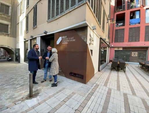 Entrada lateral del Bòlit con señalización moderna y personas conversando en la plaza