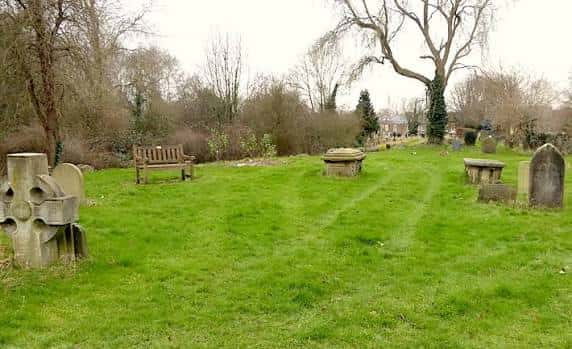 Paisaje del cementerio con bancos de madera y lápidas antiguas en un entorno natural