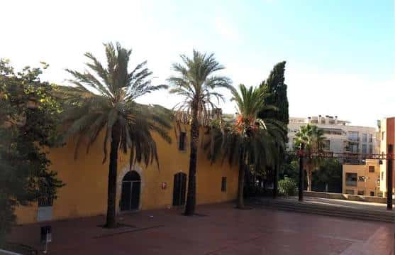 Vista exterior del Mas Fonollar con palmeras y plaza