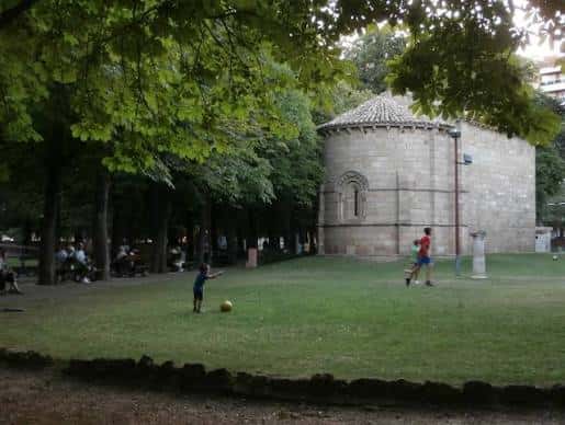 Niños jugando al fútbol junto a la ermita románica en el parque