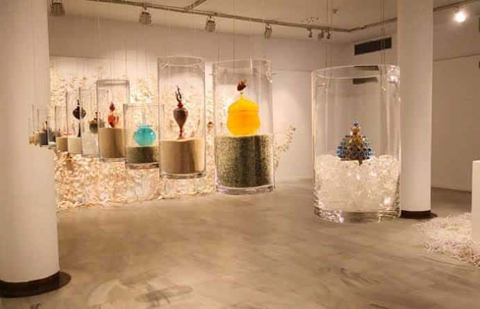 Exposición de esculturas de vidrio suspendidas en cilindros transparentes