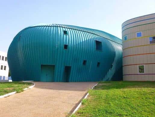 Vista exterior del Centro Cultural Viñagrande mostrando su distintiva fachada azul ondulada y la sección circular adyacente