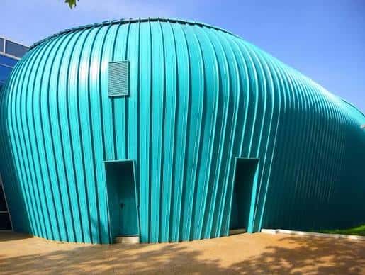 Detalle arquitectónico de la estructura azul metálica con textura corrugada y puertas de acceso