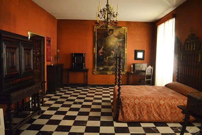 Habitación con cama de cuatro postes y suelo de damero