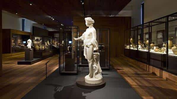 Sala de exposiciones con estatuas y vitrinas de artefactos arqueológicos