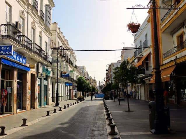 Vista diurna de la Calle Ancha en Sanlúcar de Barrameda, con arquitectura tradicional y comercios locales